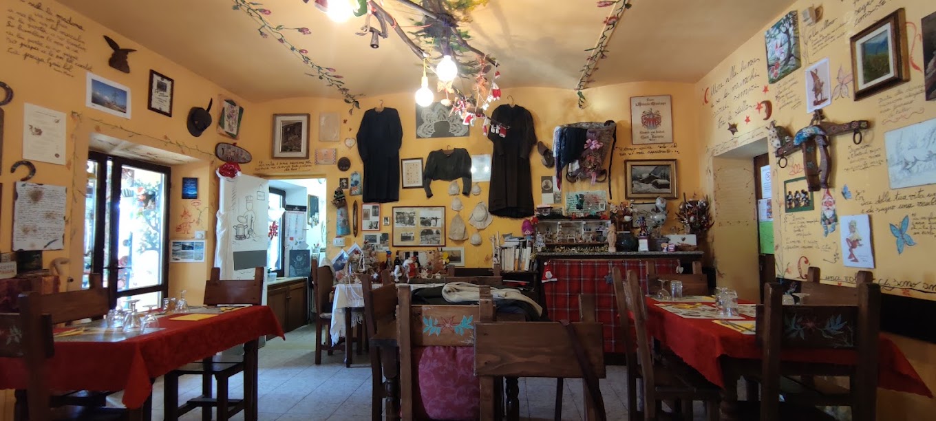 La sala del Faunet con tavoli in legno, tovaglie rosse e pareti piene di ricordi di montagna