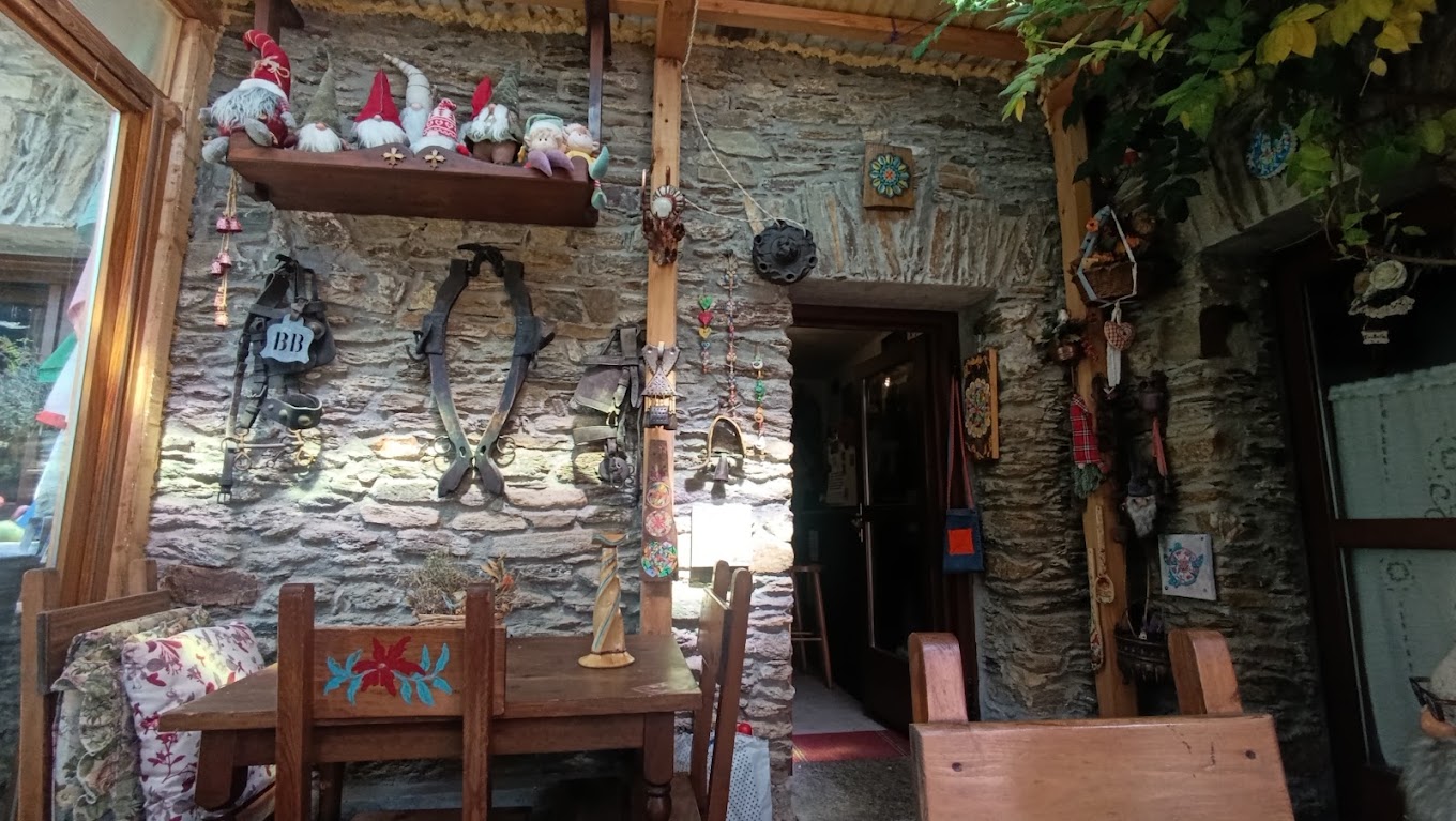 Tavolo esterno del Faunet sotto il porticato, tra muri in pietra e oggetti della tradizione